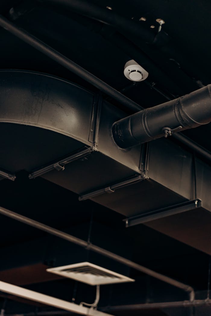 why-choose-us-02 Detailed view of industrial air ducts on a ceiling, showcasing modern urban design.